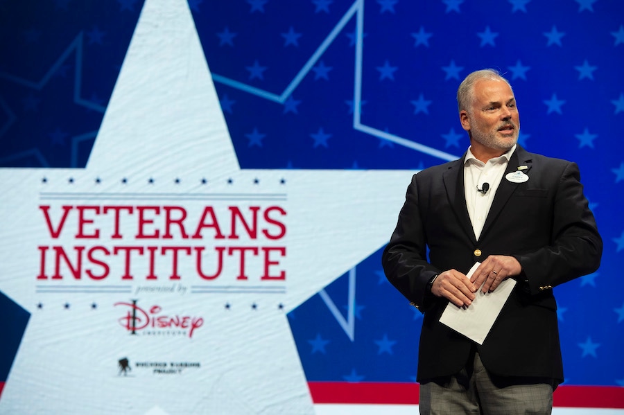 US Navy Veteran giving a speech in front of Veterans Institute Sign