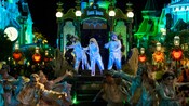 Assorted ghouls dance on and around a parade float that is styled to look like the Haunted Mansion